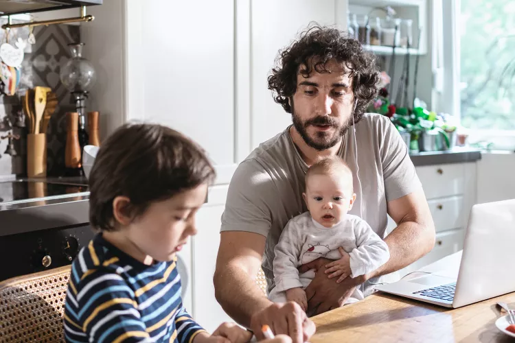 Picture of Dad working from home while also looking after children
