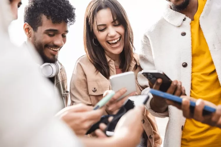 Young group of teens using phones and talking with eachother