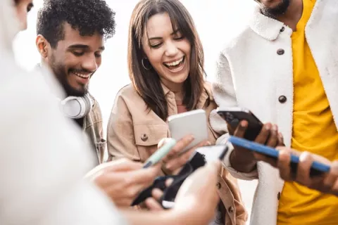 Young group of teens using phones and talking with eachother