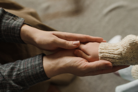 Parent holding child's hand in a supportive way